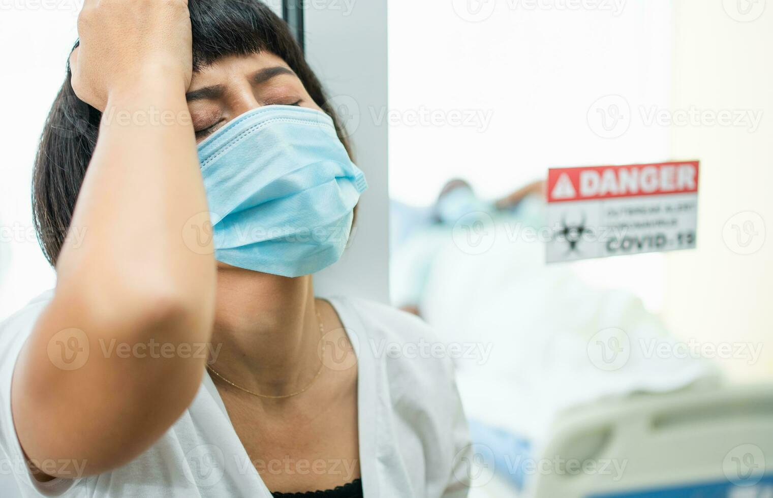 A Wife standing in front of the Quarantine room And Hold your head with her hands While waiting for the examination results, She has anxiety. Concept of Disease treatment and coronavirus vaccine photo
