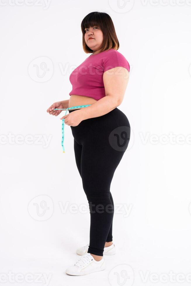 An overweight woman measures her belly fat on a white background. Concept of healthy, food for  health and lifestyle photo