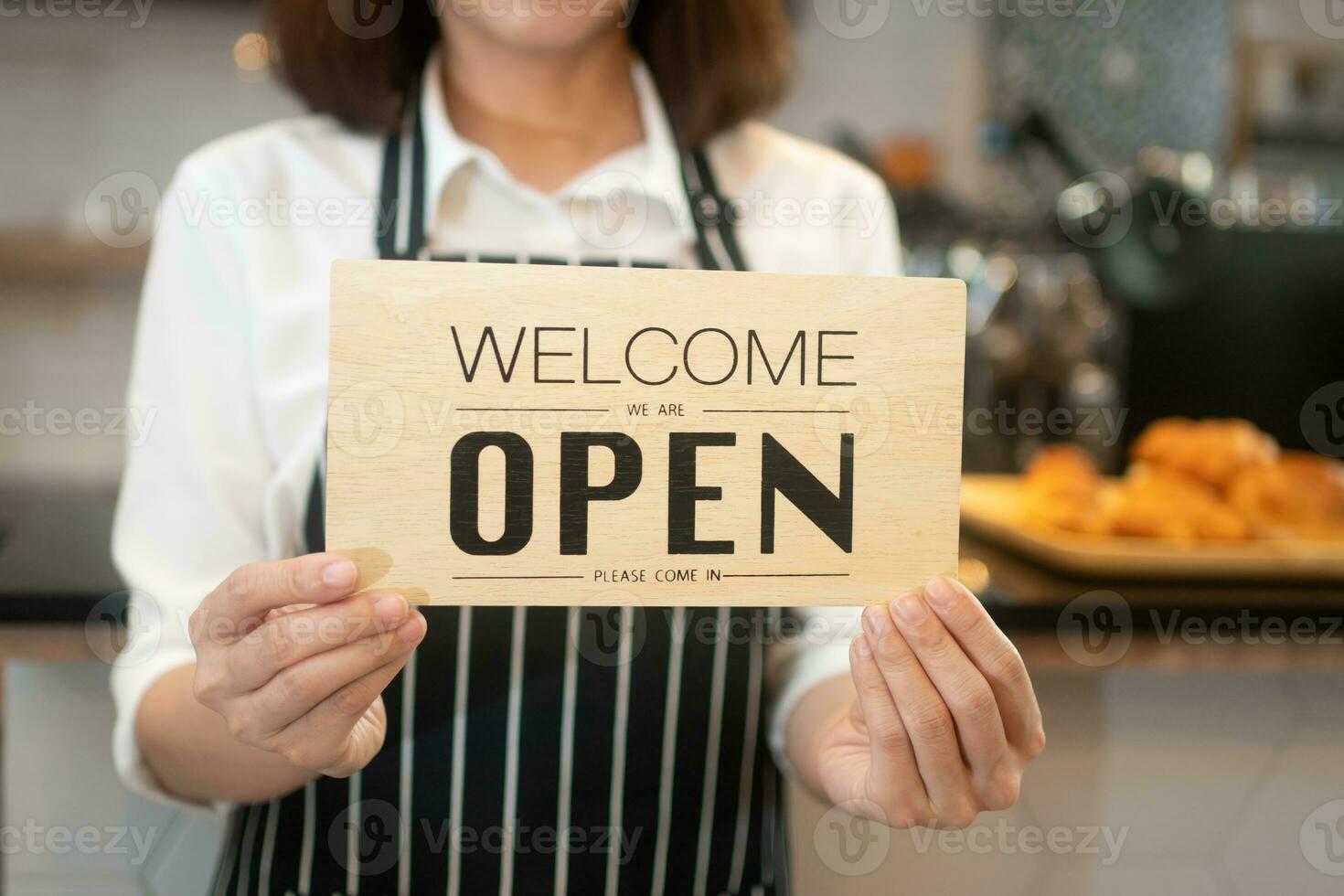 Portrait of a happy woman Asian waitress standing at a coffee shop holding open sign while reopening care during coronavirus pandemic, Small business owner and startup with a cafe shop concept photo