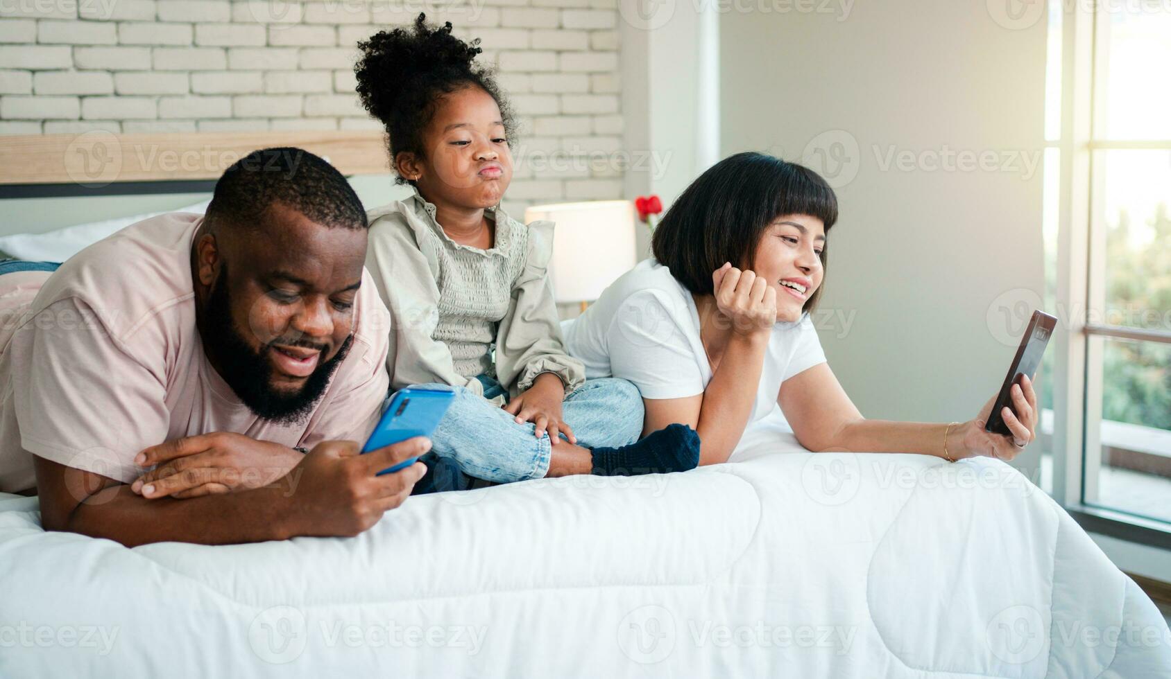 African American girls are not satisfied and sad, sitting in the middle between father and mother. Parents Are using the smartphone and abandoned children. Children need their parents attention. photo