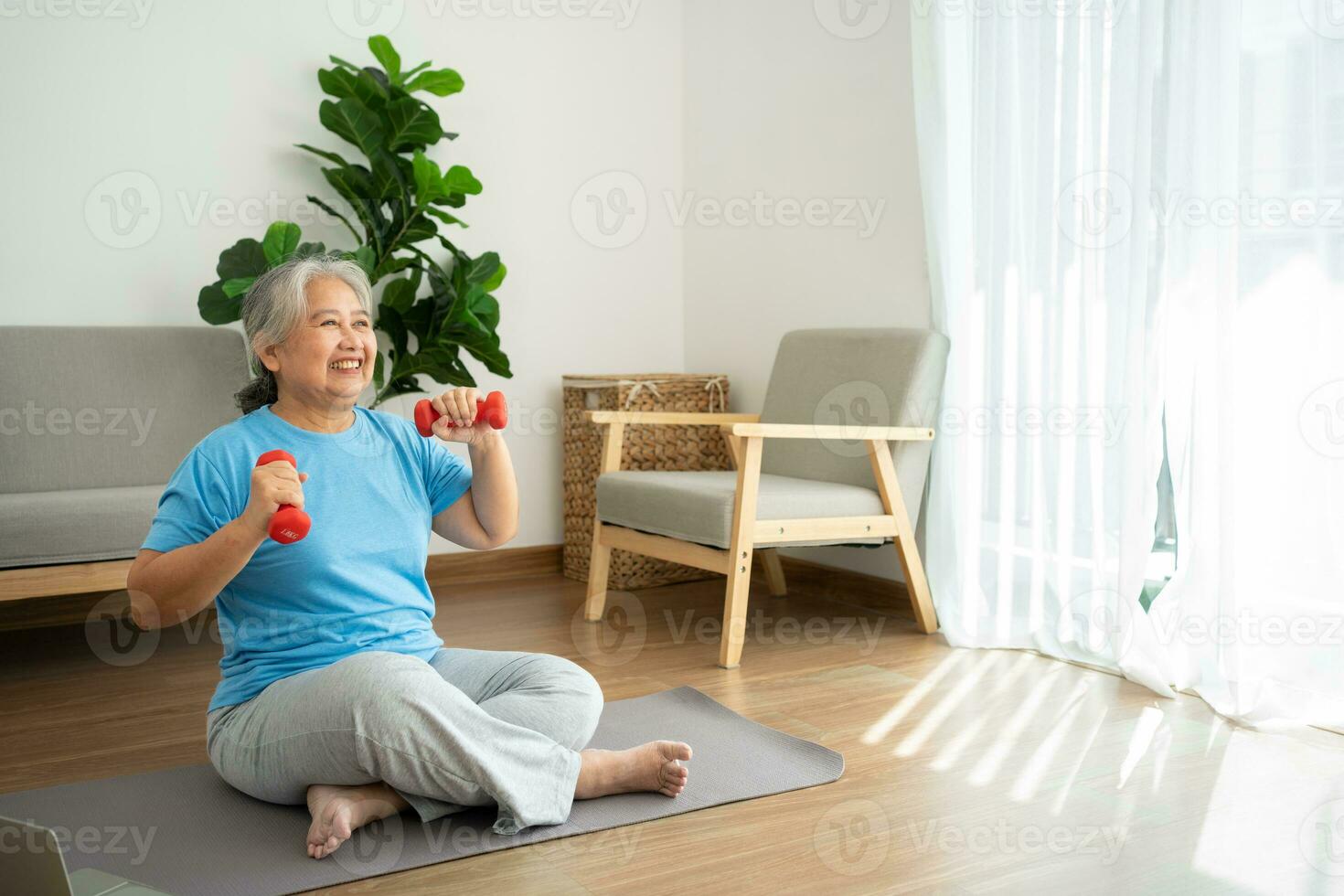 Asian senior woman lifting dumbbell for exercise and workout at home. Active mature woman doing stretching exercise in living room. Exercise Active and healthy for older, elder, and senior concept. photo