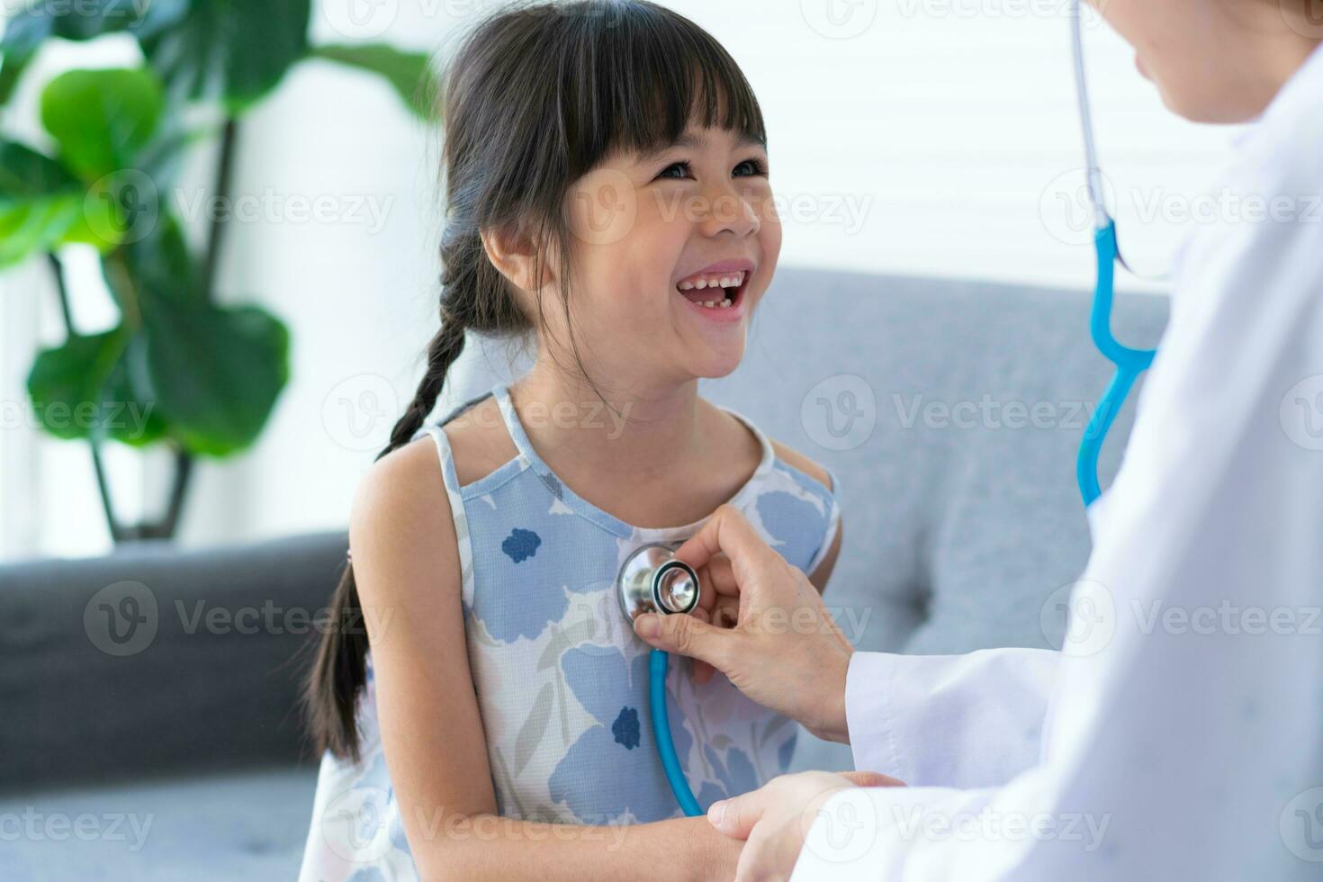 Asian woman pediatrician doctor hold stethoscope for exam a little girl patient and heck heart lungs of kid, Good family doctor visiting child at home, Healthcare and medicine for childhood concept. photo