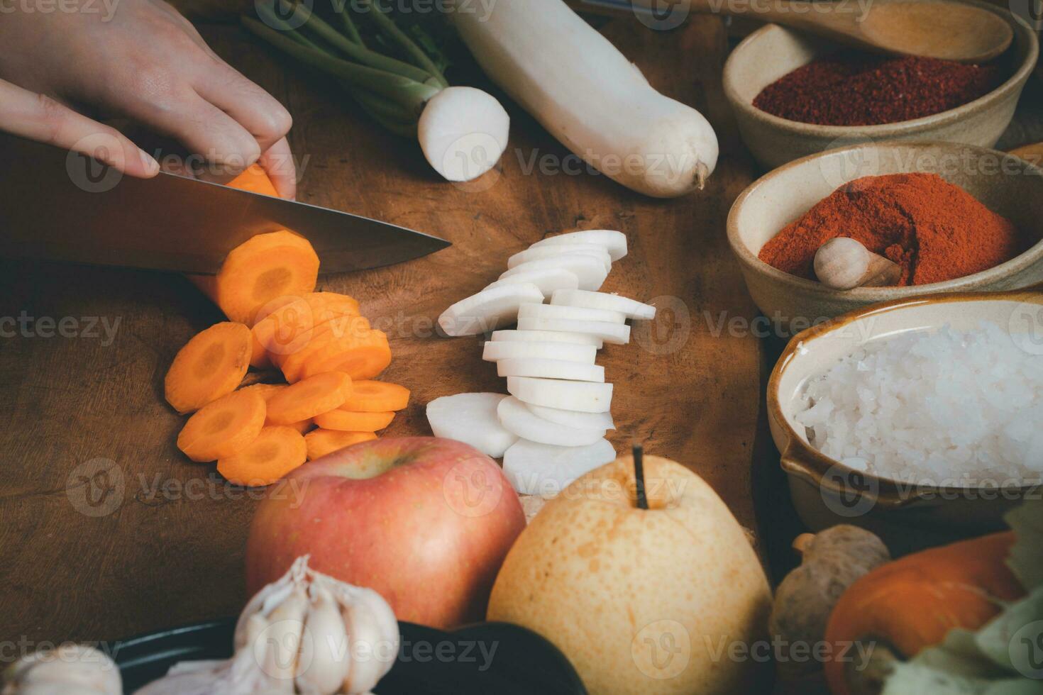 Asian women wearing Korean traditional costumes hanbok are mixing fresh stir-fry and kimchi ingredients with ingredients such as salt, garlic, gochugaru, fresh vegetables. photo