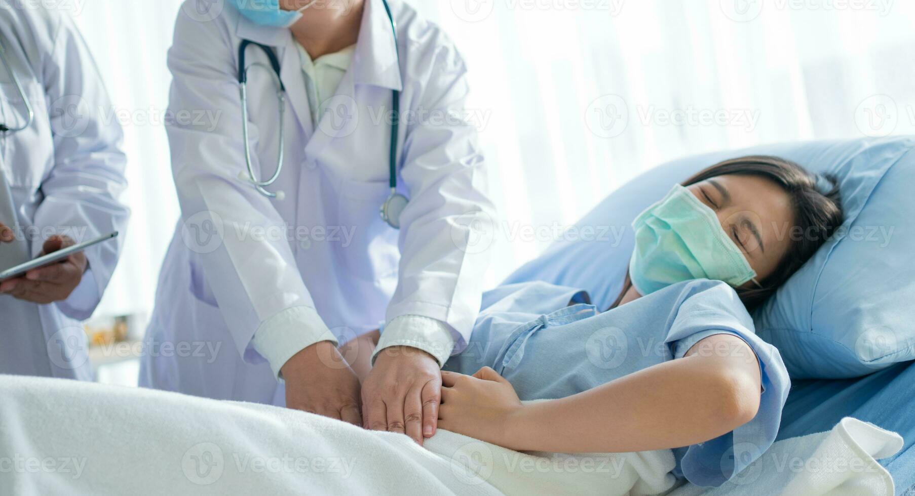 Group of Doctor try to help patient woman lie on hospital bed and holding on stomach suffering. Abdominal pain that comes from menstruation, diarrhea, or indigestion. Sickness and healthcare concept photo