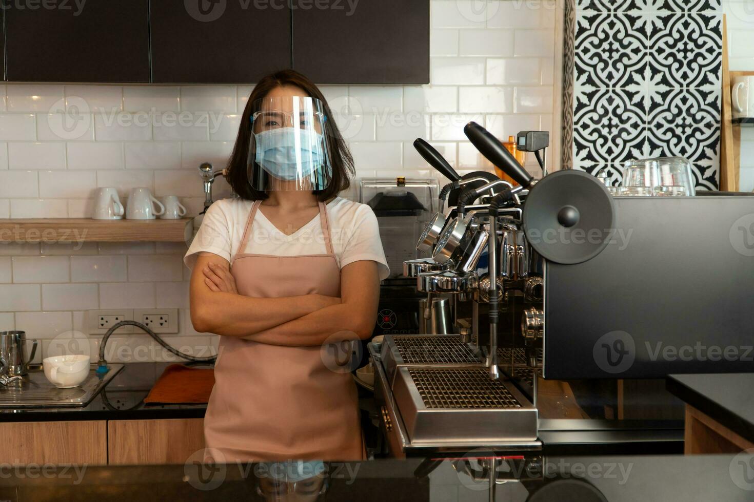Portrait of a happy woman Asian waitress wearing a face mask and  standing at a coffee shop, Small business owner and startup with a cafe shop concept photo