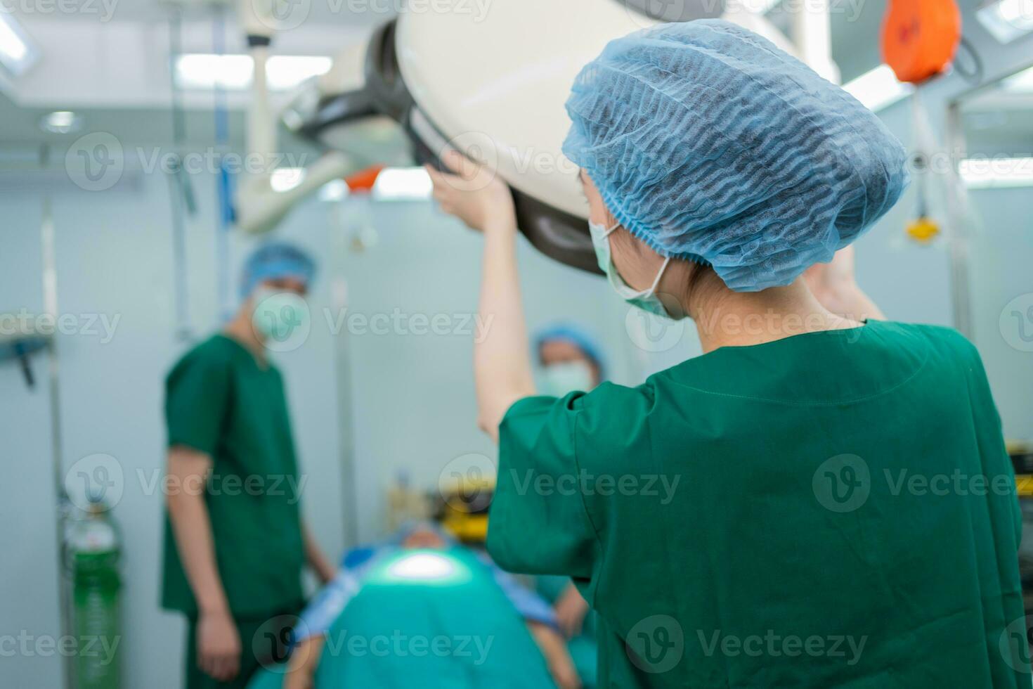 detrás de un cirujano asiático con una máscara médica de pie en el quirófano de un hospital. equipo de cirujanos profesionales. salud, concepto de servicio médico de emergencia foto