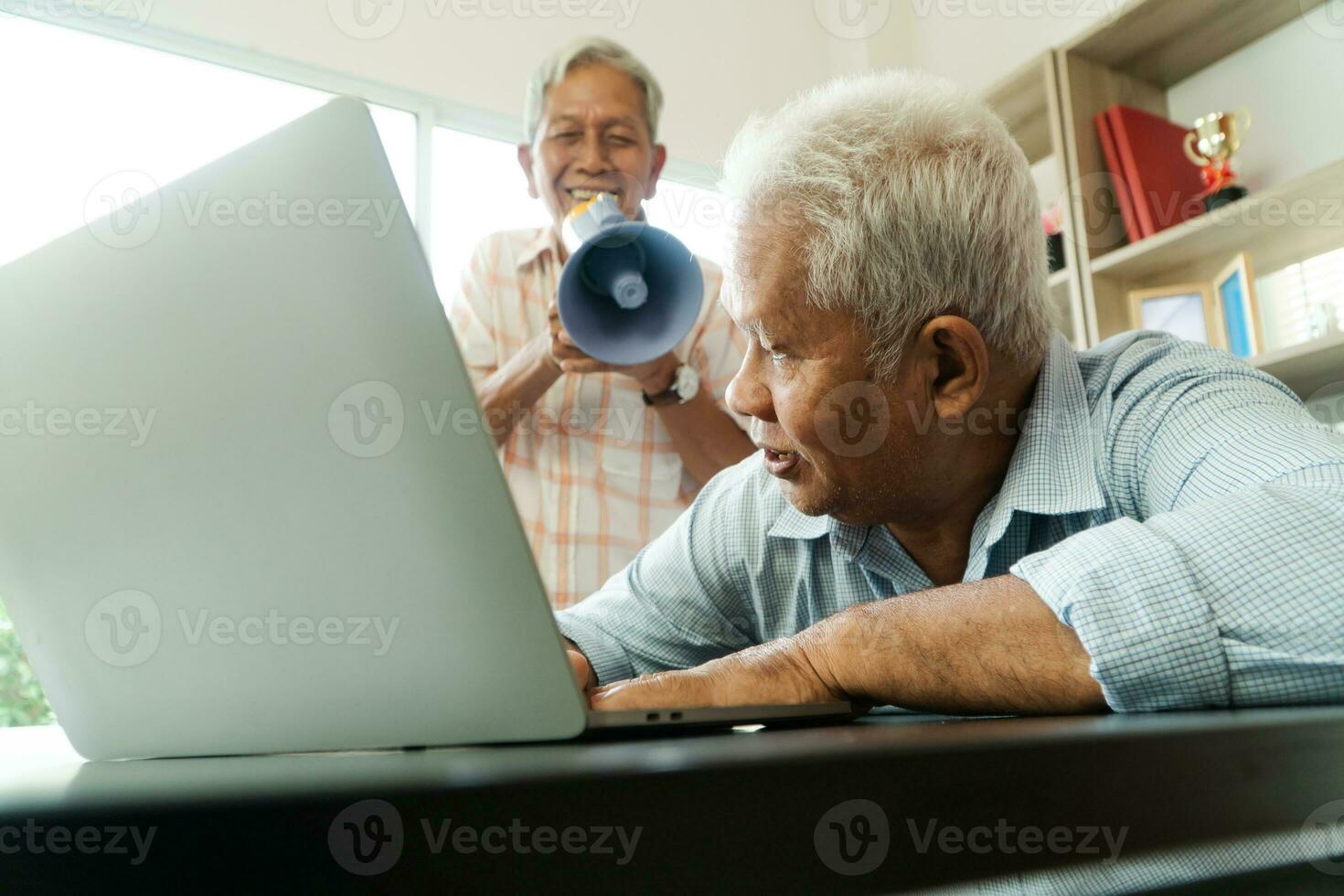 Old Asian elderly yell to a megaphone to talk with a friend for communication. Concept of communication problem in aging cause of ear be without hearing, deaf photo