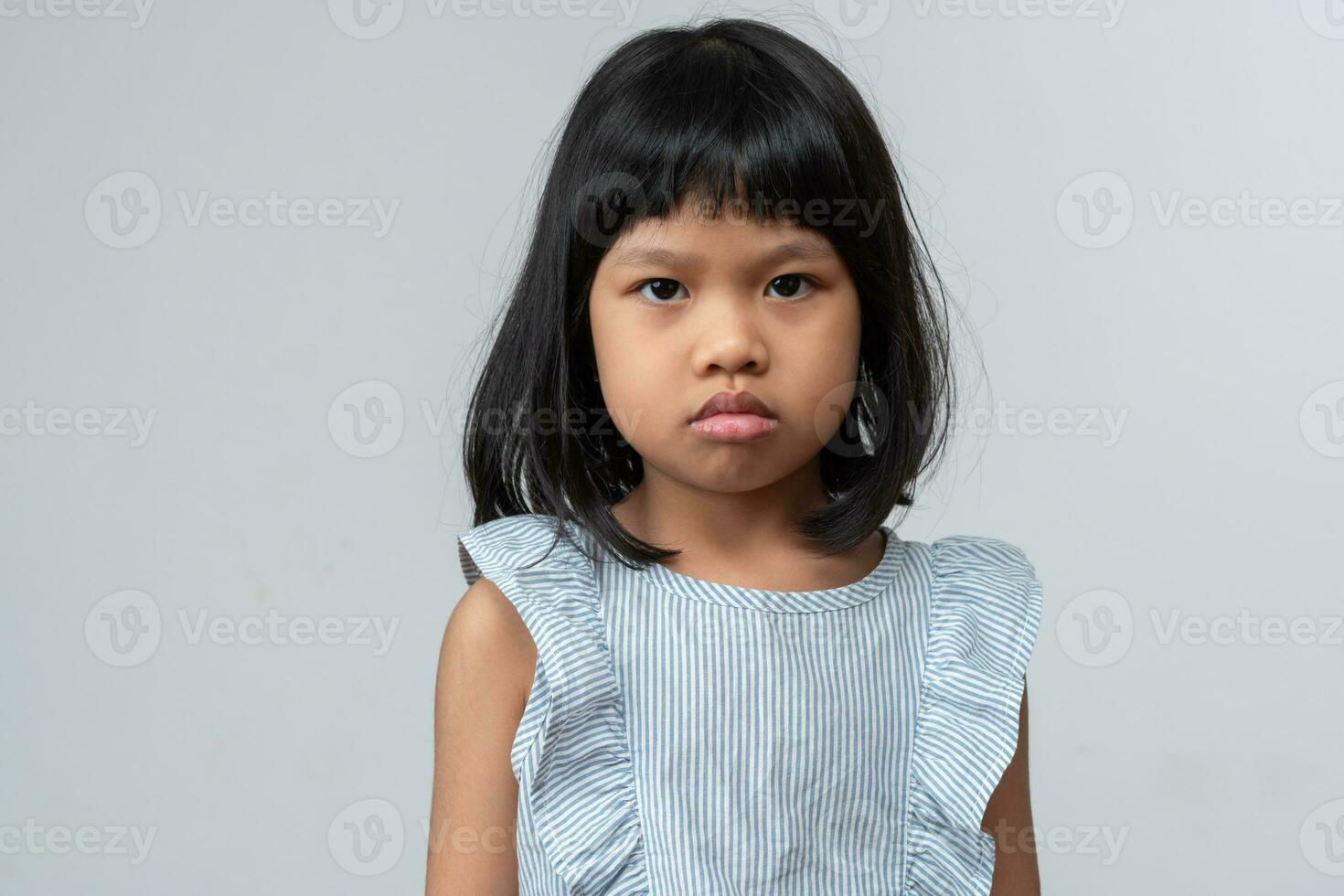 Portrait of Asian angry and sad little girl on white isolated background, The emotion of a child when tantrum and mad, expression grumpy emotion. Kid emotional control concept photo