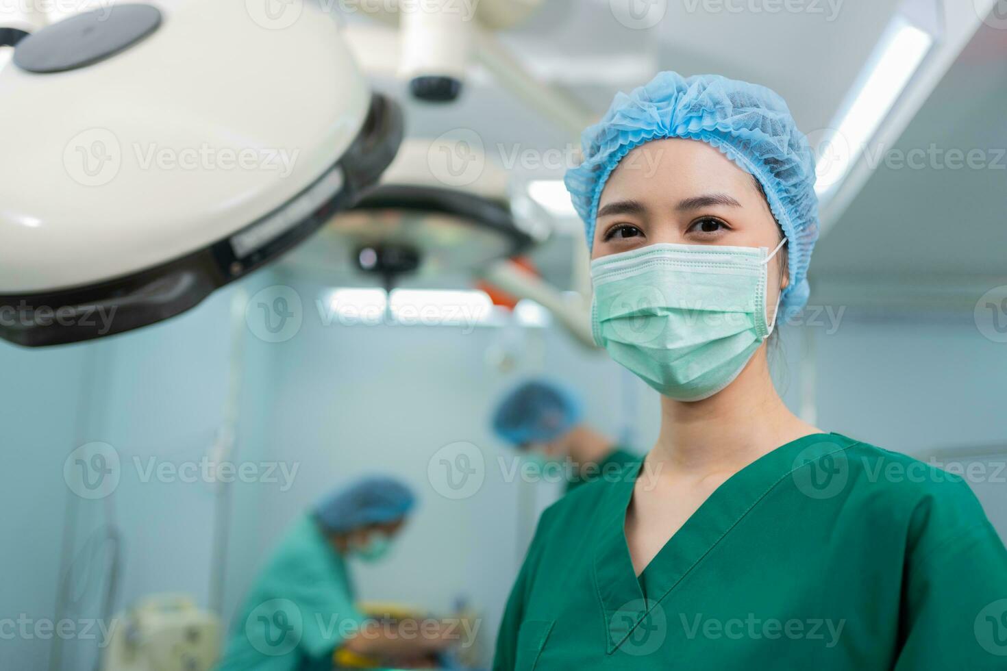 Portrait of Asian woman surgeon with medical mask standing in operation theater at a hospital. Team of Professional surgeons. Healthcare, emergency medical service concept photo