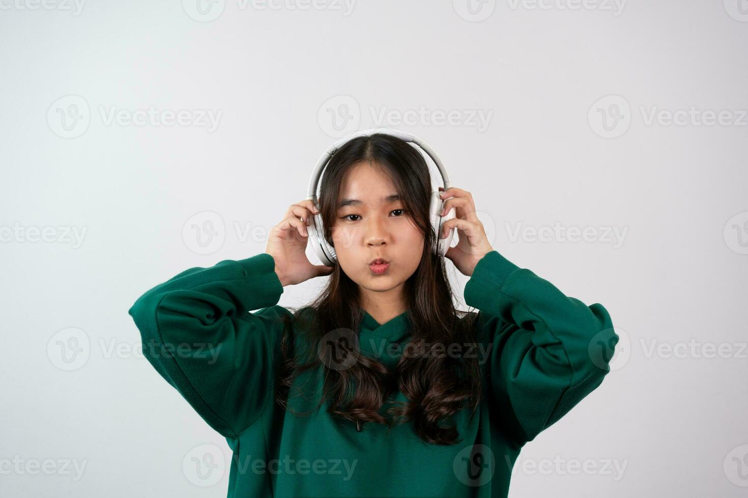 A happy attractive carefree pleased teenage girl has fun,  relaxing dancing and smiling, joyfully with raised arms, being entertained and amused isolated on a white background. photo