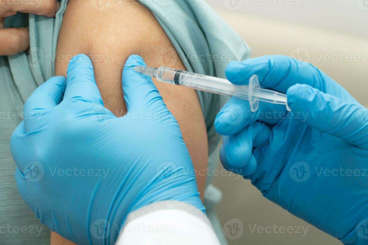 Doctors wear medical masks and vaccinated to senior women patients for the prevention of coronavirus and flu. Concept of immunization from inoculation photo