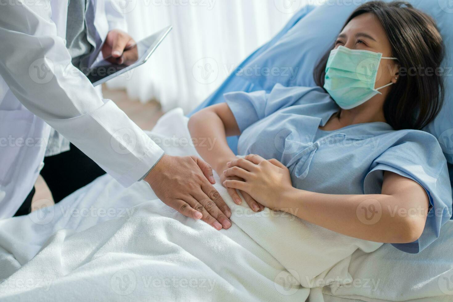 Group of Doctor try to help patient woman lie on hospital bed and holding on stomach suffering. Abdominal pain that comes from menstruation, diarrhea, or indigestion. Sickness and healthcare concept photo