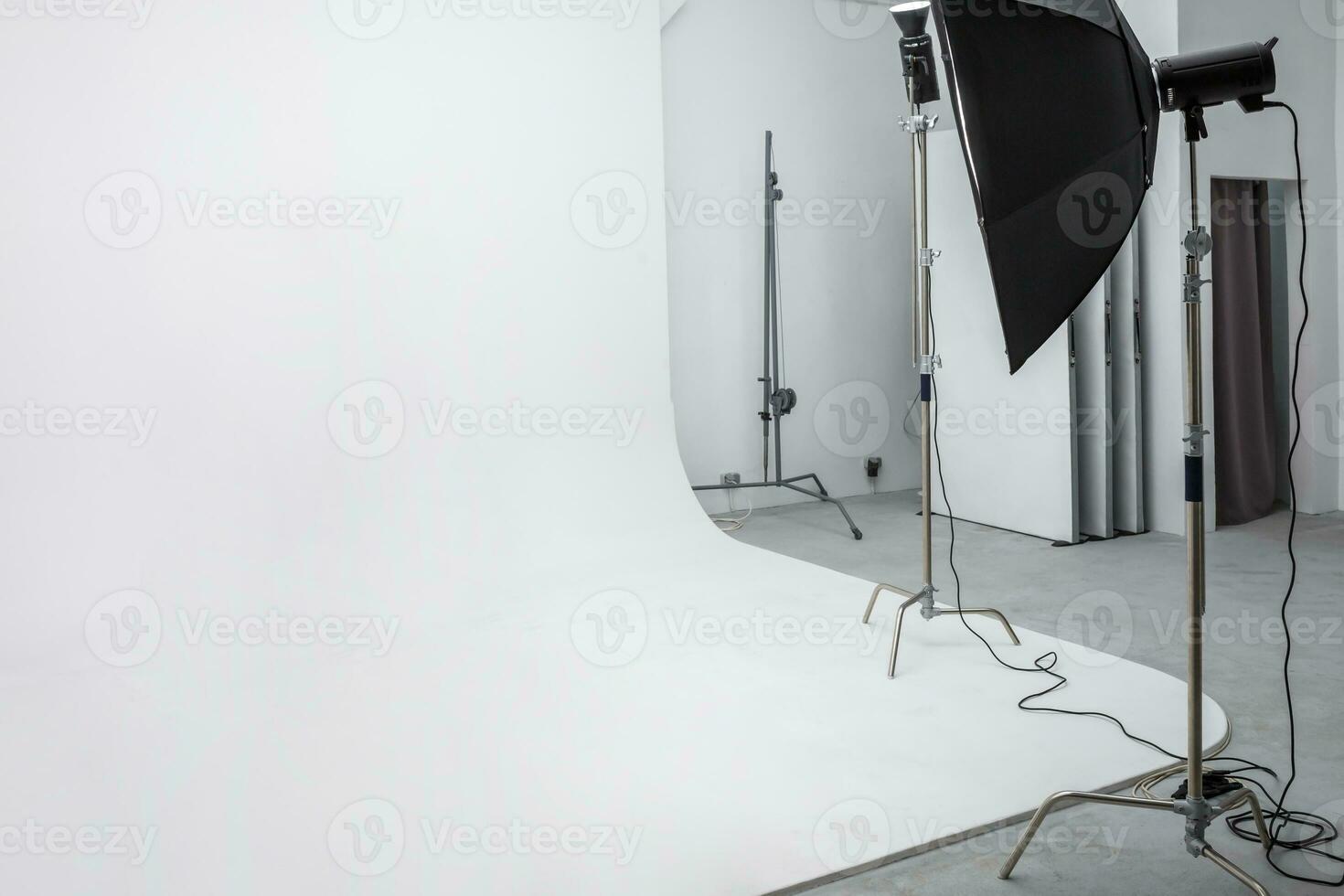 interior of bright space of photo studio with large white cyclorama with lighting equipment