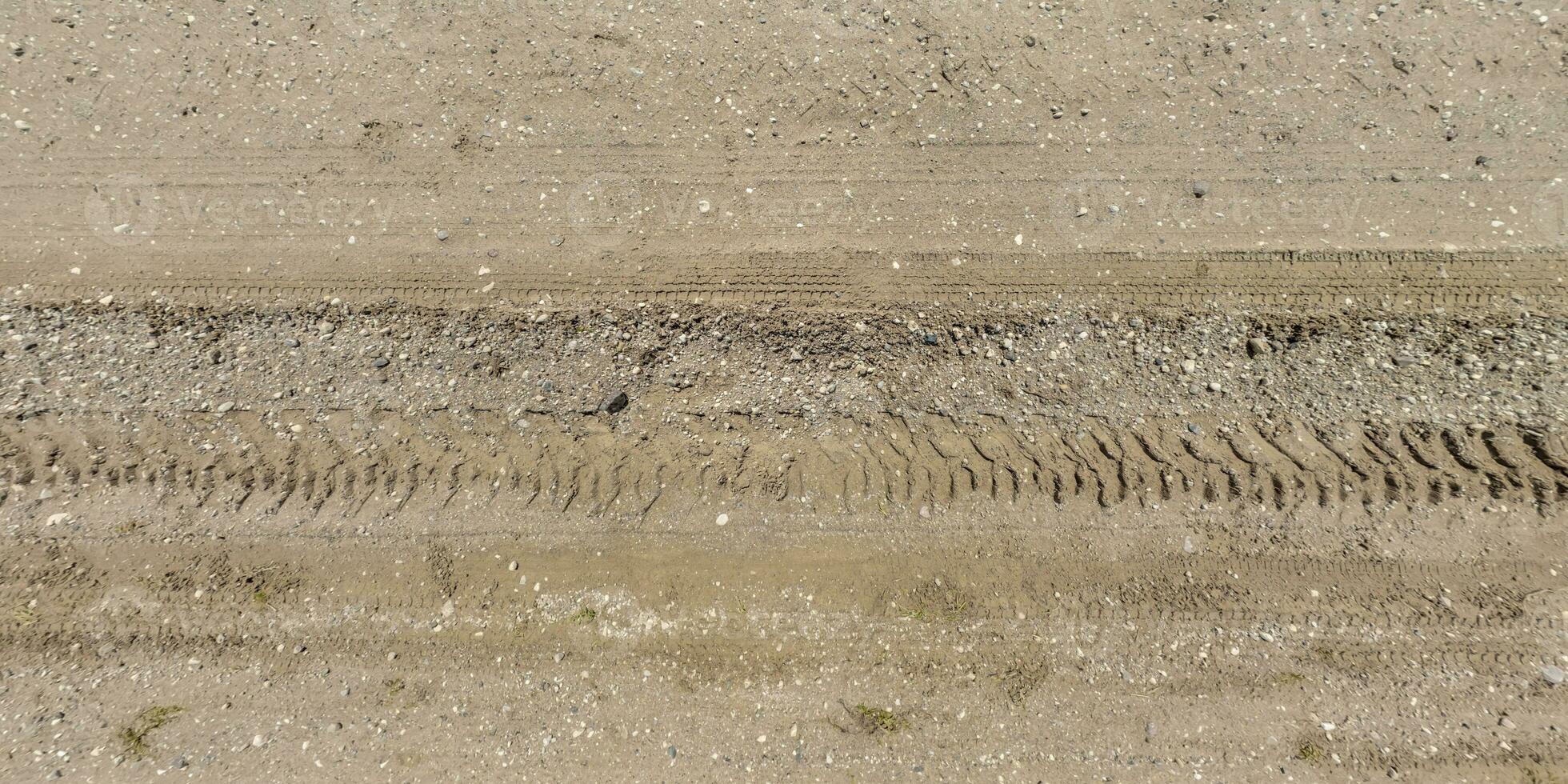 panorama of surface from above of gravel road with car tire tracks. photo