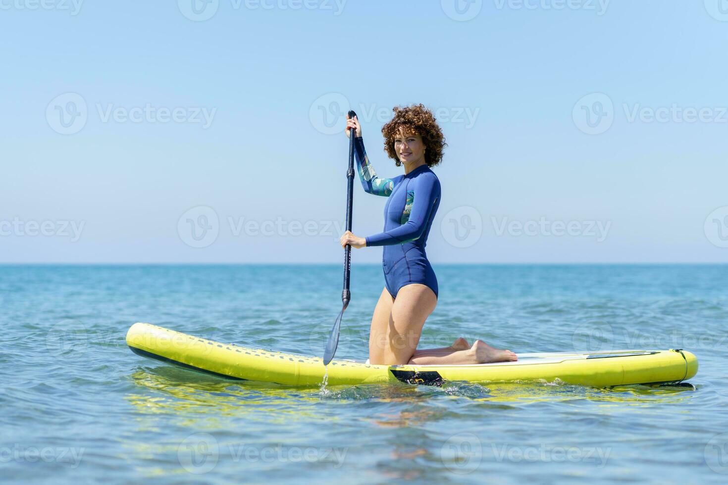 sonriente mujer con paleta arrodillado en cenar tablero en mar foto