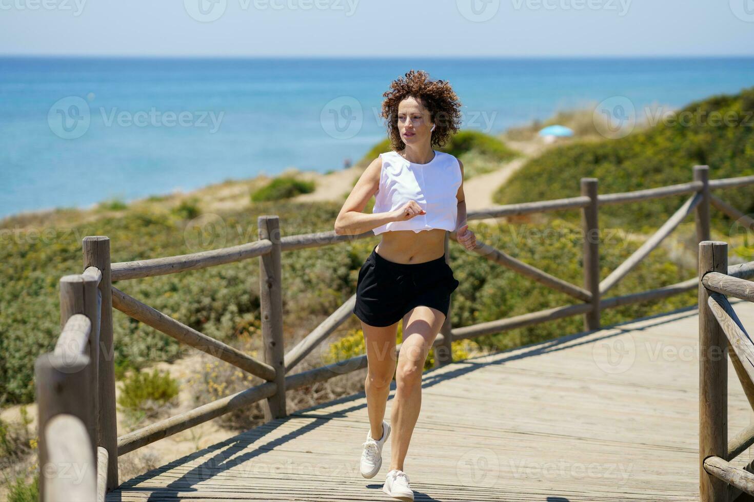 Active woman in sportswear jogging near ocean photo