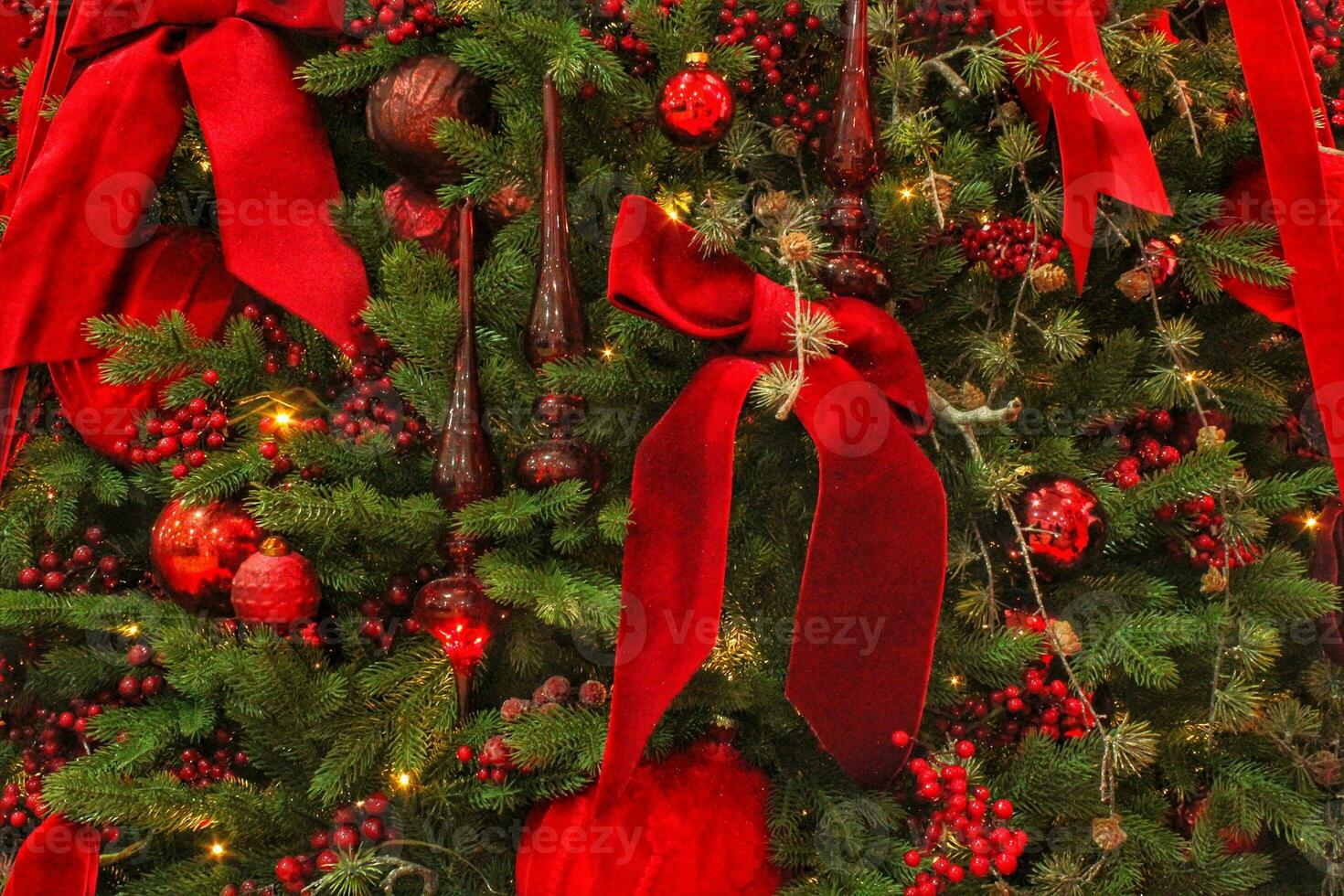 Close-up of Christmas tree in the house with decoration. Garland, lights, baubles, rowan and ribbon bows on spruce fir branches. Winter holidays composition photo