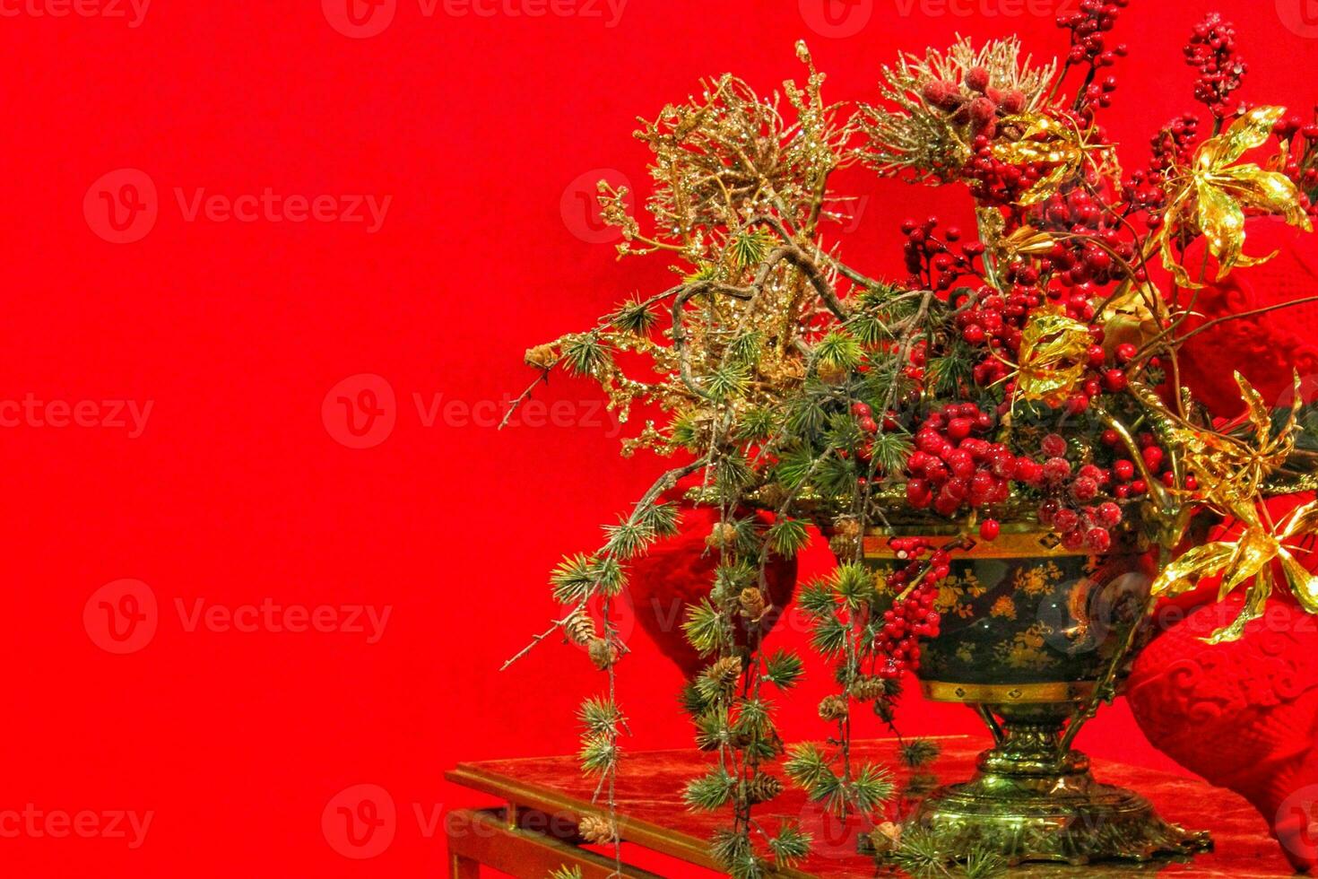 Close-up of Christmas tree branch decoration on table of living room. Garland, golden flowers, lights and rowanberries on spruce fir branches. Winter holidays composition with copy space photo