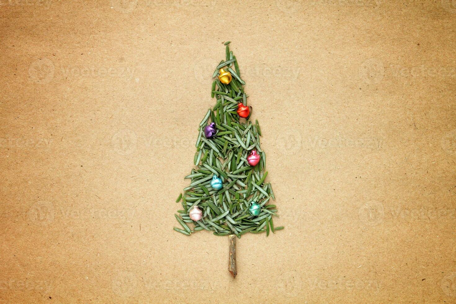 Green srpuce needles Christmas tree pattern with jingle bells on craft recycled paper. Ecological minimal design for holiday postcard. Eco friendly, zero waste, diy, nature concept. Flatlay, top view photo