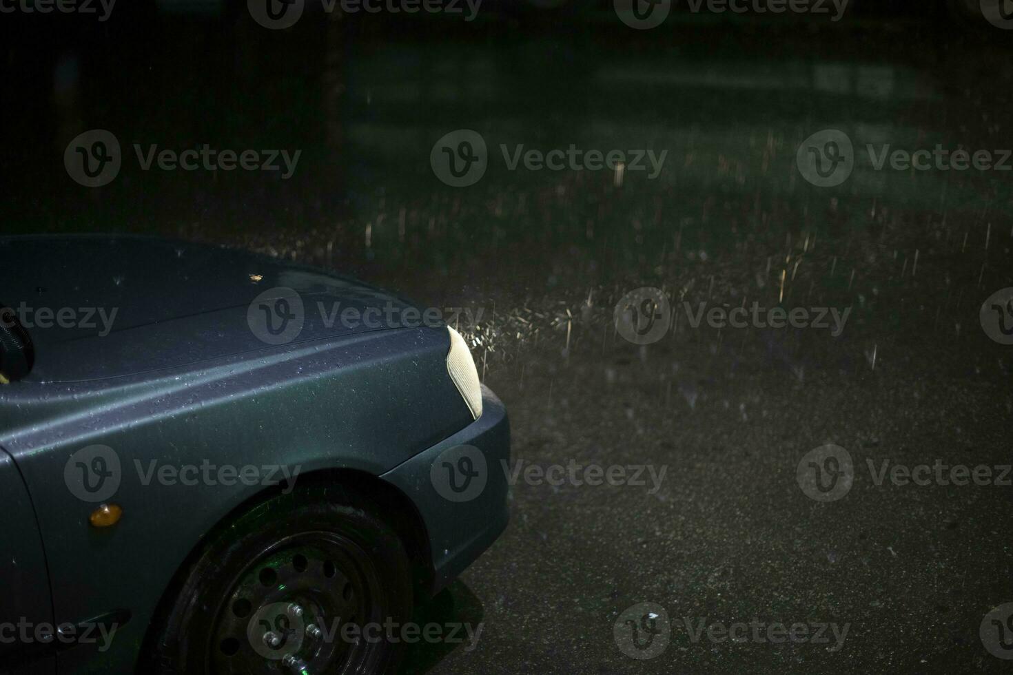 Car in rain. Lamp of car shines through raindrops. Trip at night in storm. photo