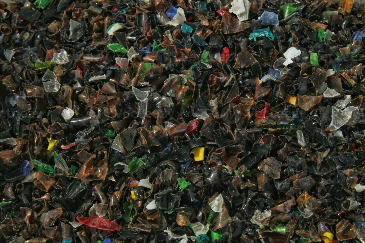Shredded plastic pieces prepare for recycling. Raw cables material for reproduction. Sorting garbage on waste plant. Pile of scrap bottles on trash storage factory. Environmental concept photo