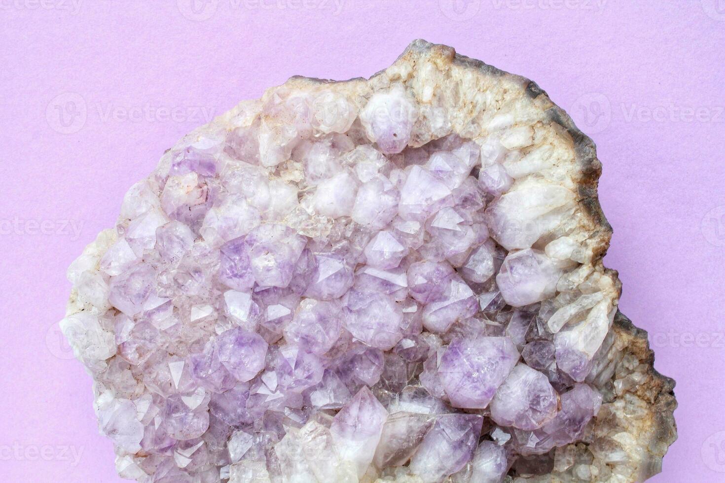 Violet amethyst gemstone crystal mineral on purple background with copy space. Natural stone. Geological sample of druse. Healing pebble photo