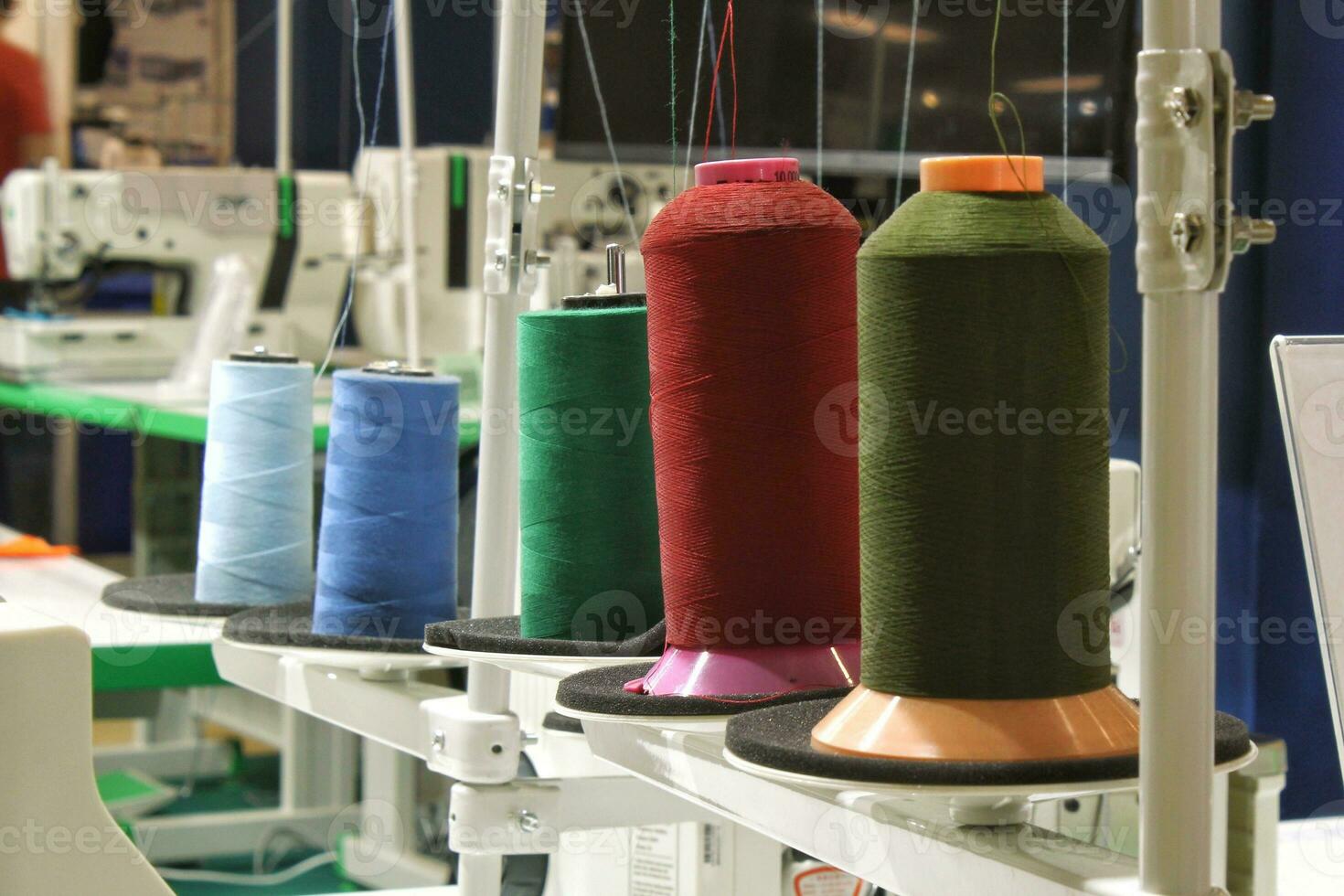 Close-up of spools of color threads, spinning machine. Yarn bobbins making in a textile factory. Embroidery machine in garment industry. Dyeing fabrics yarn. Sewing material tool photo