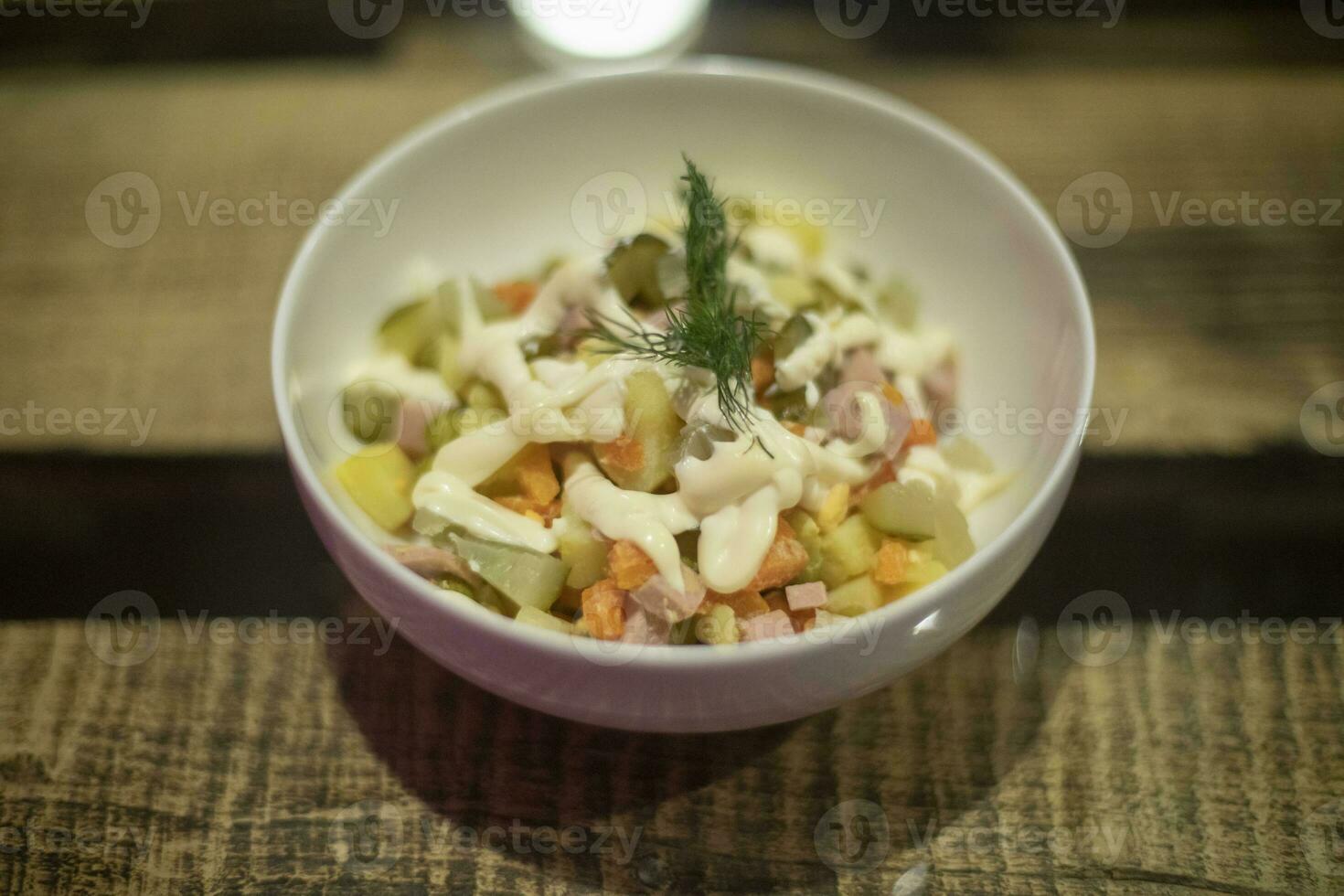 Salad with mayonnaise. Salad in plate. Olivier on table. photo