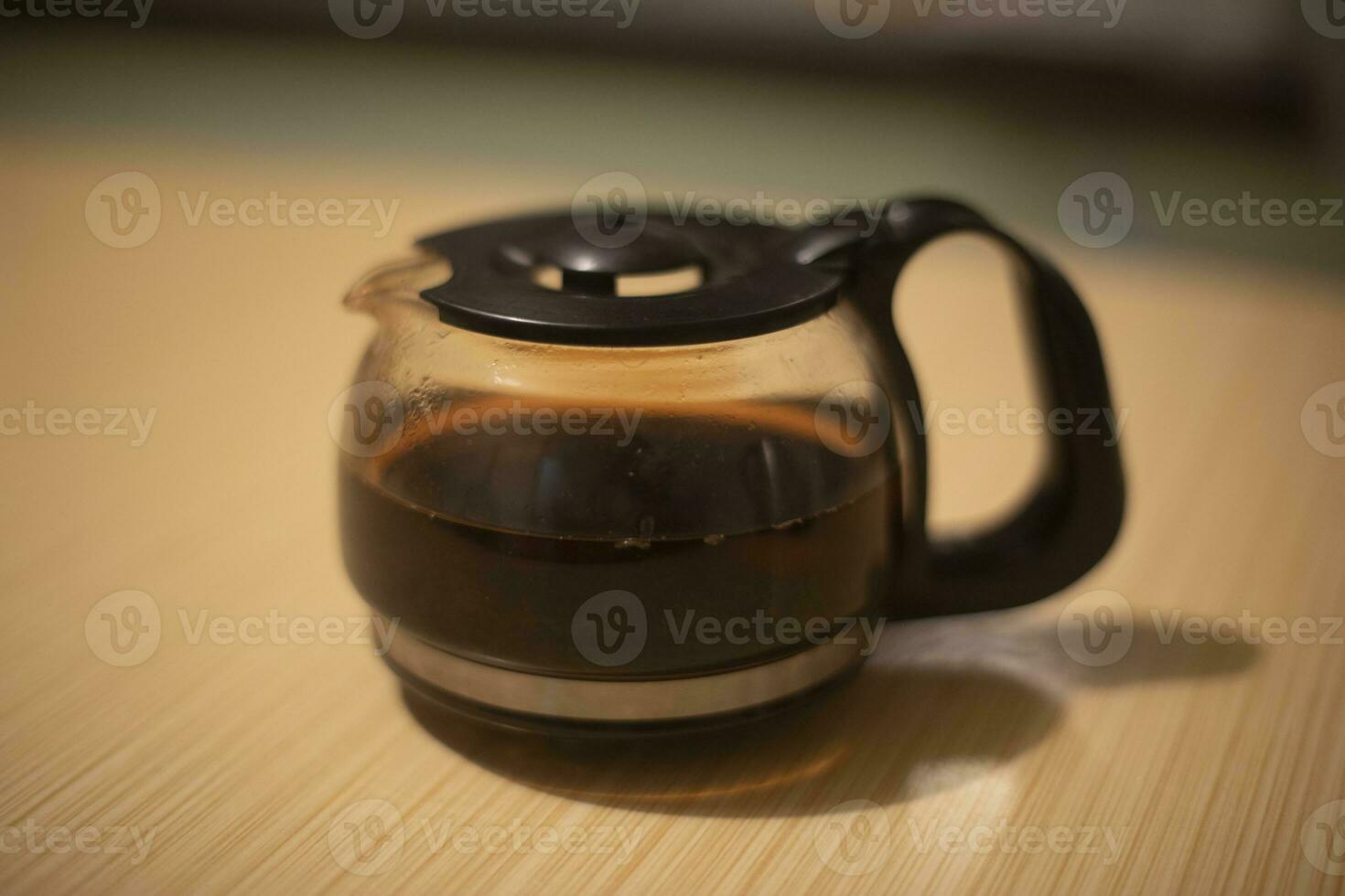 Kettle with coffee. Coffee's on table. Hard liquor. Transparent teapot. photo