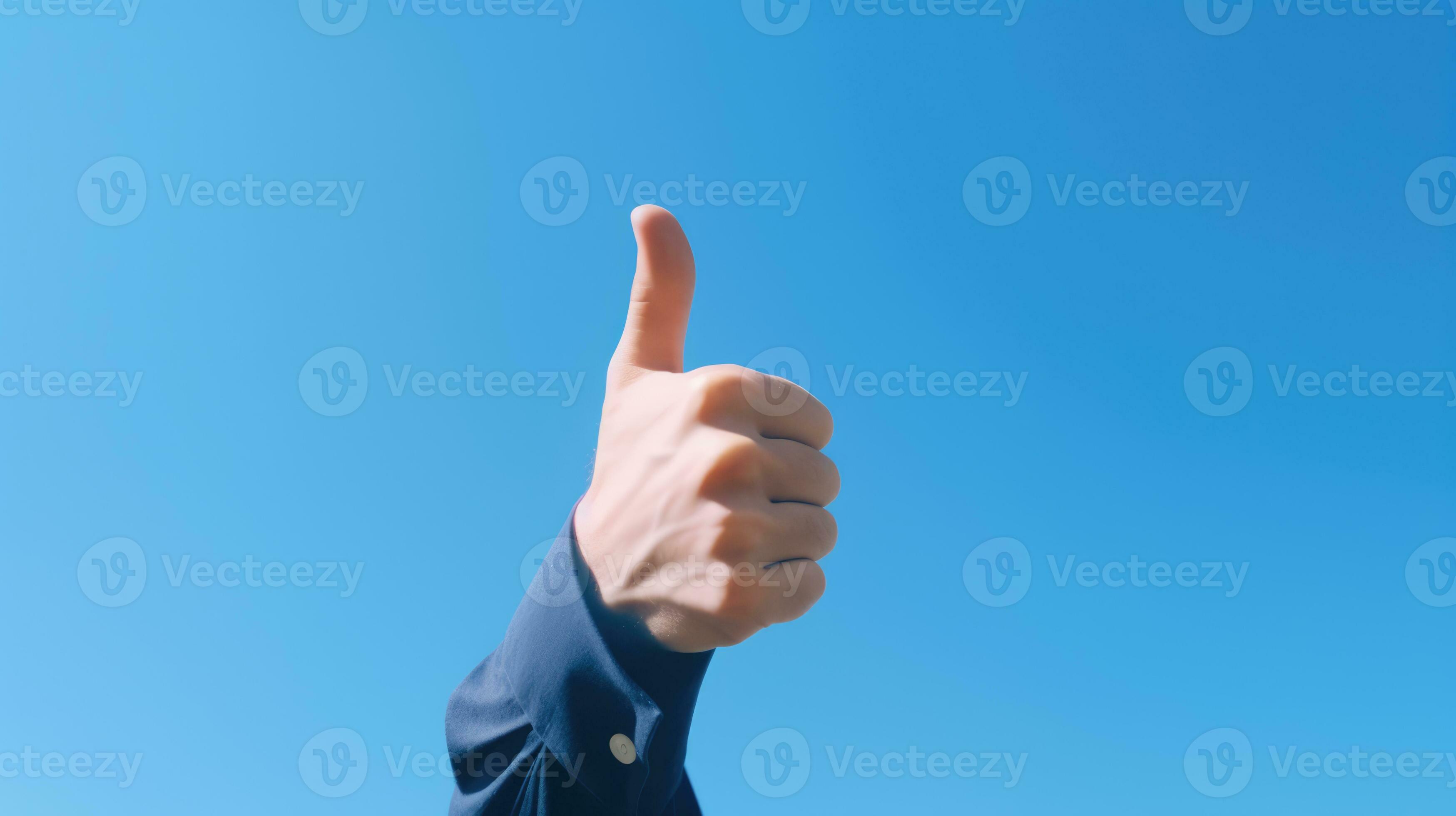 an adult hand giving a thumbsup gesture against a clear, blue sky. The