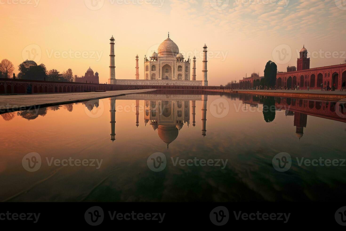 the breathtaking Taj Mahal monument as the sun sets, creating a stunning reflection in a nearby pool. The warm hues of the sunset illuminate the scene, highlighting photo