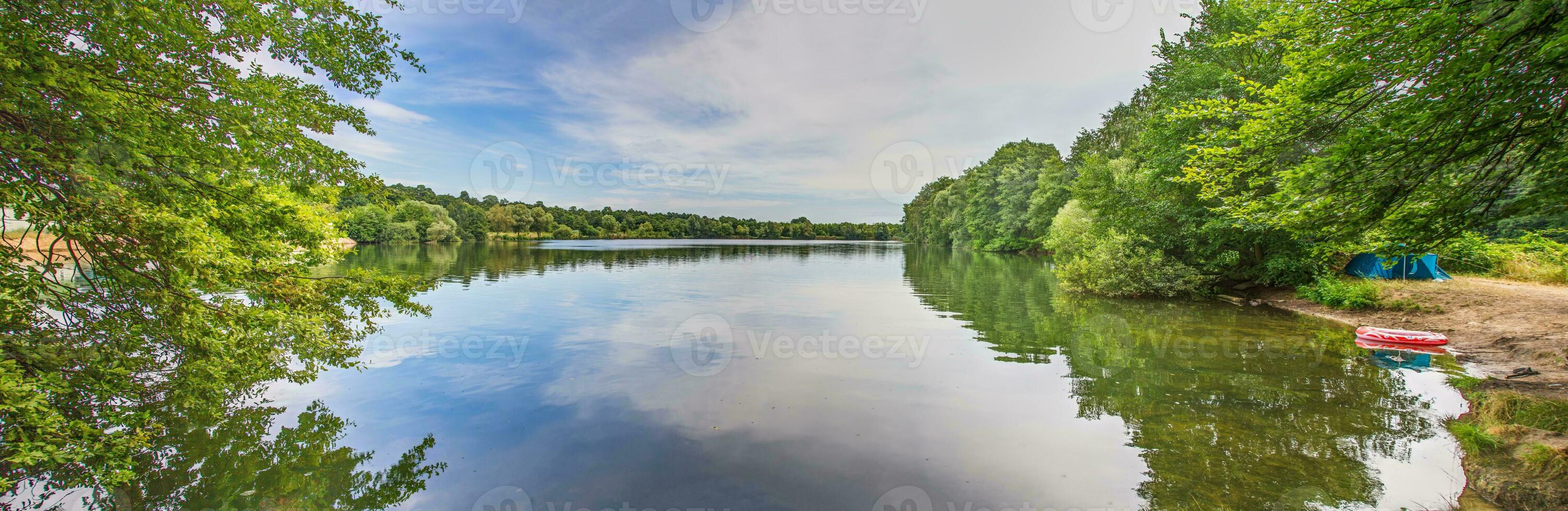 Panoramic view over lake with lush shore vegetation in summer photo