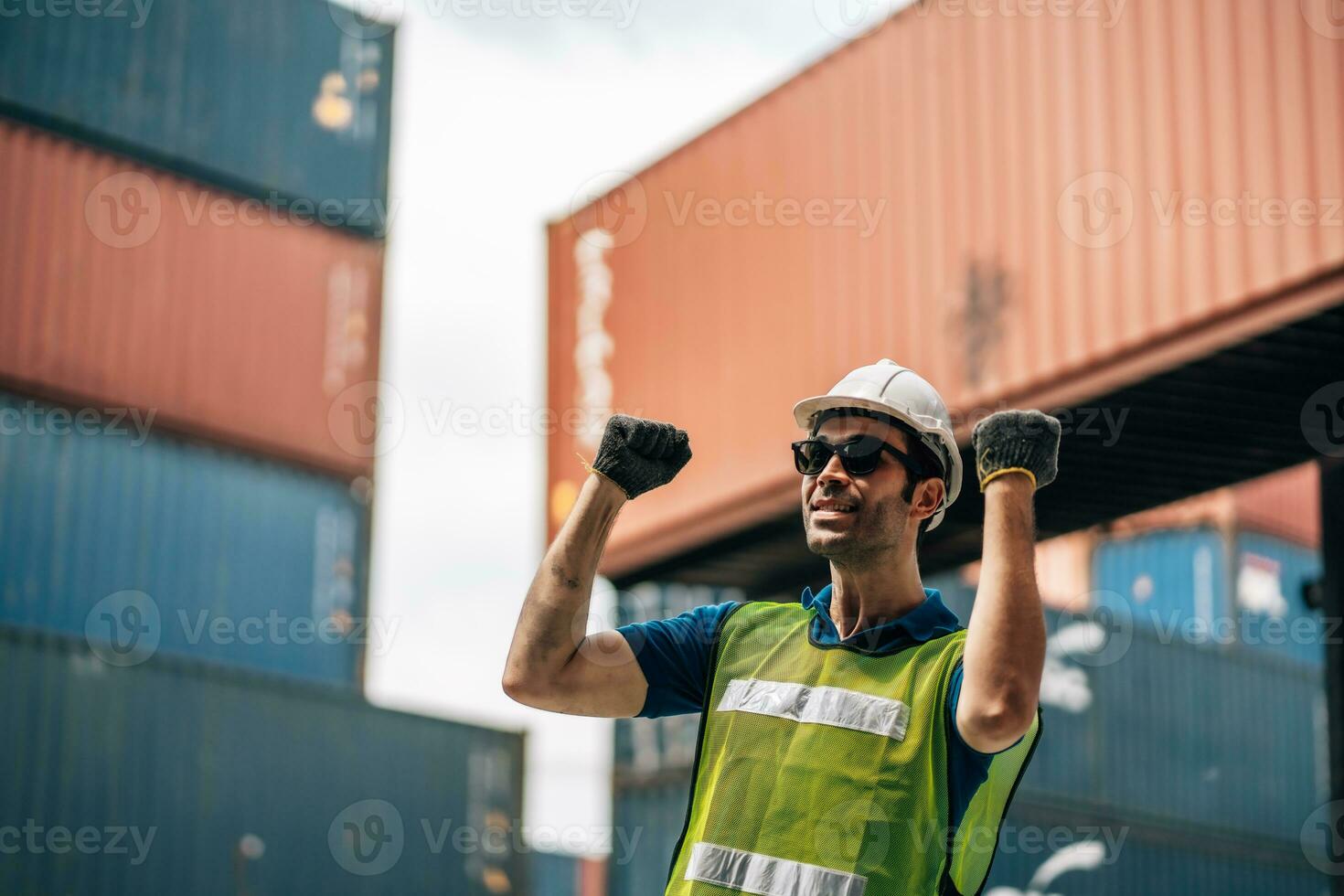 Portrait of Smiling Professional Heavy Industry Engineer Worker Wearing Safety Uniform and Hard Hat. In the Background container Industrial Factory shipment photo