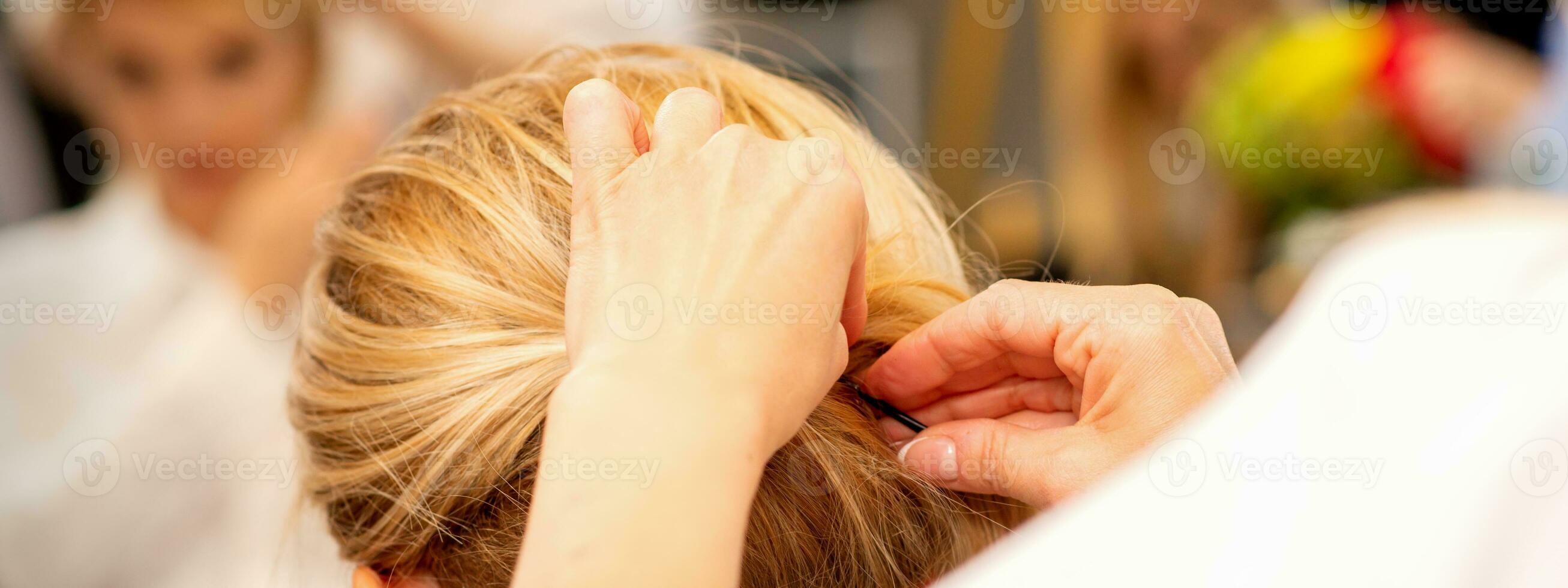 Hair stylist's hands doing professional hairstyling of female long hair in a beauty salon. photo