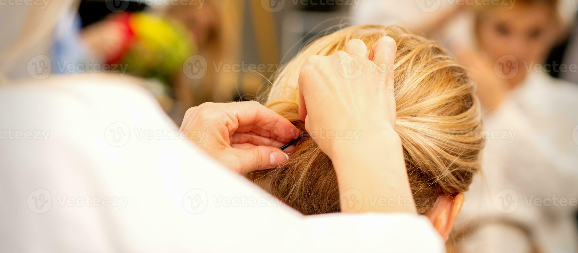 Hair stylist's hands doing professional hairstyling of female long hair in a beauty salon. photo