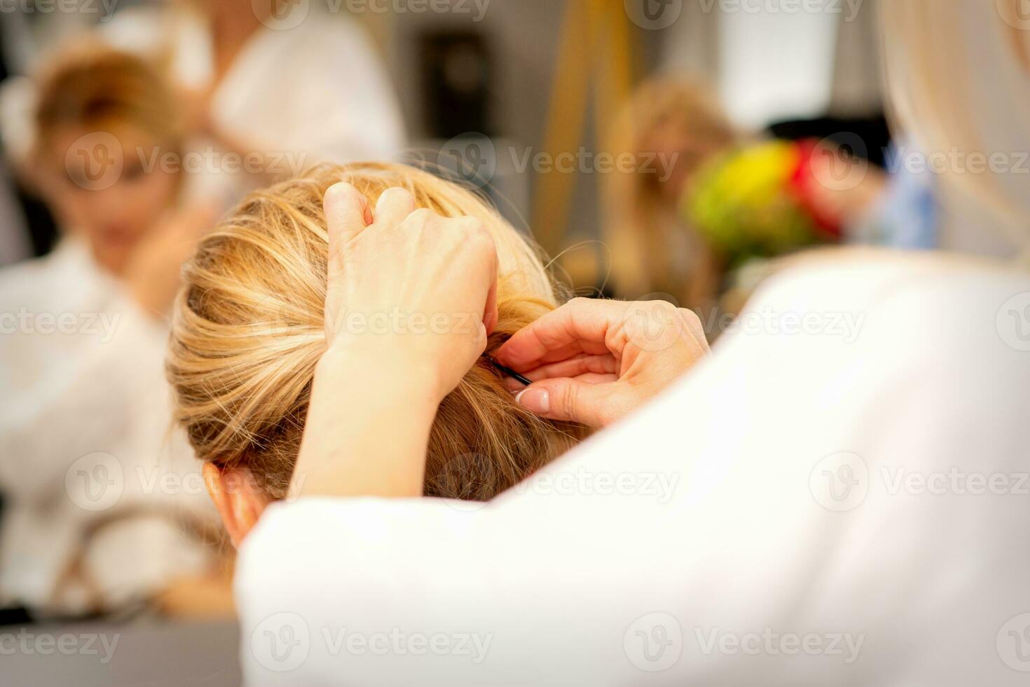 Hair stylist's hands doing professional hairstyling of female long hair in a beauty salon. photo
