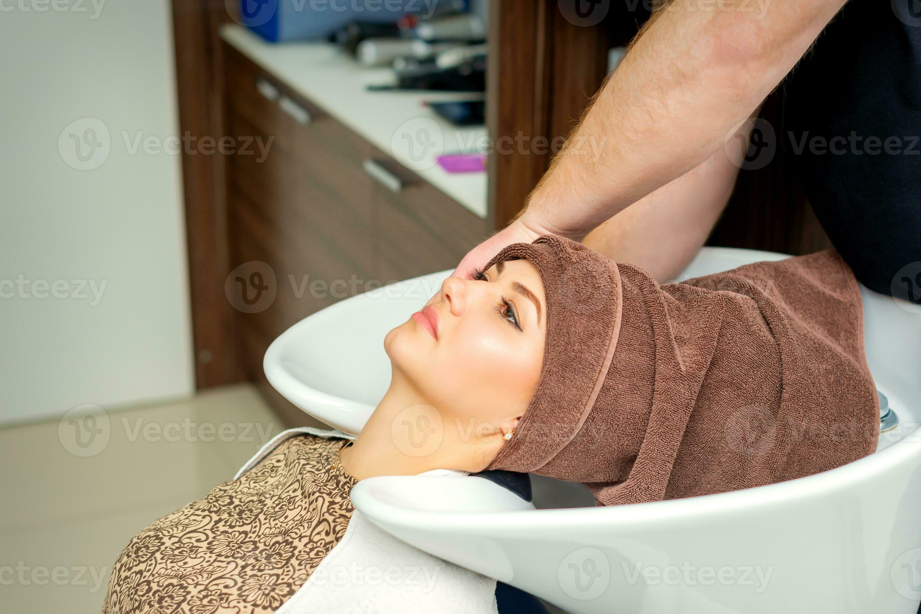 young relaxed woman getting her wet hair wrapped in a towel