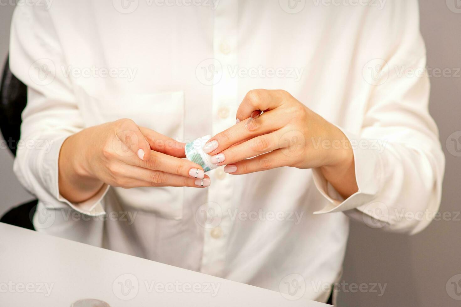 Manicure master's hands with beautiful manicure holding case box with nail sequins in nail salon. photo