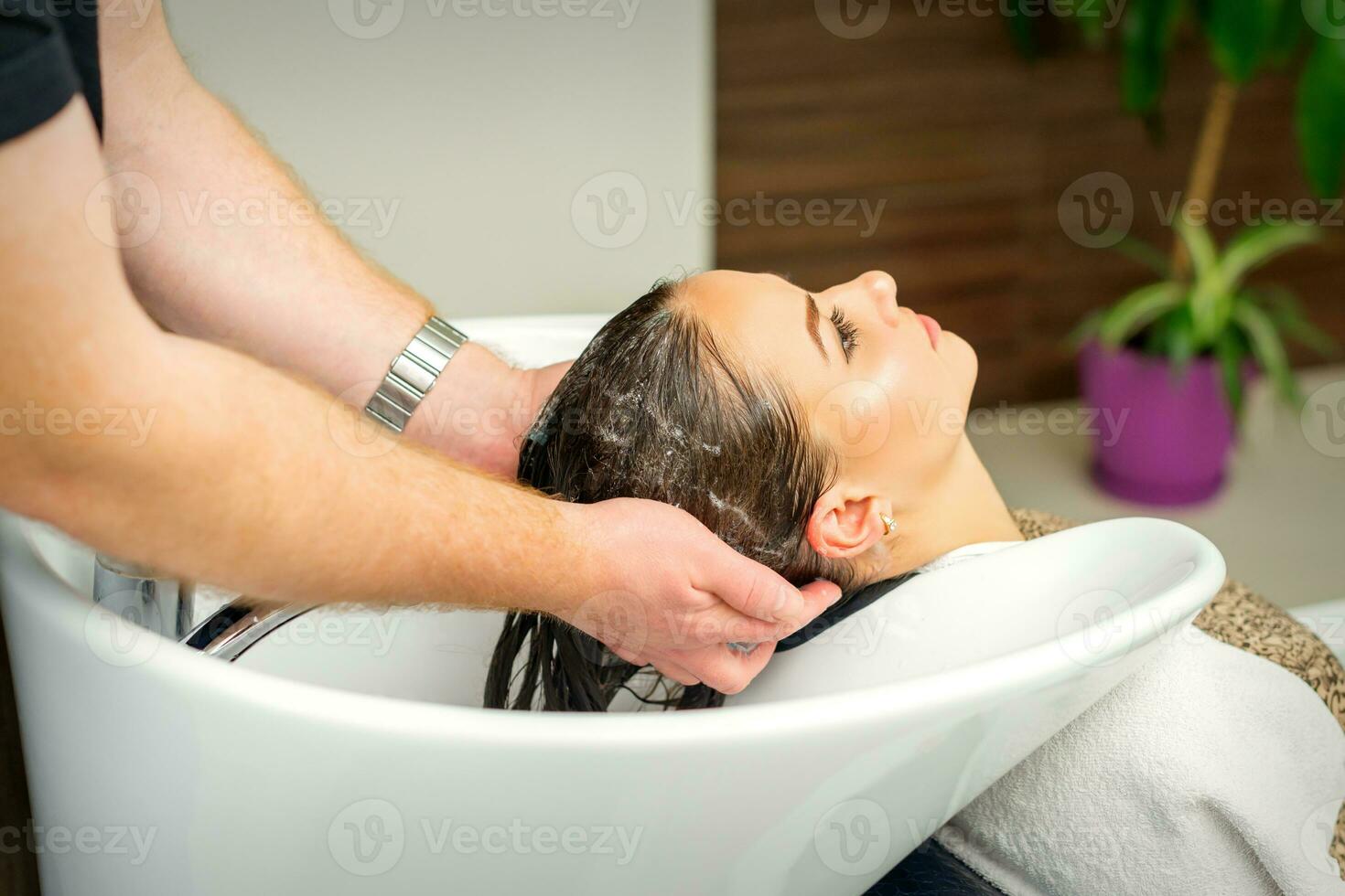 Beautiful caucasian woman washing hair in a beauty salon. photo