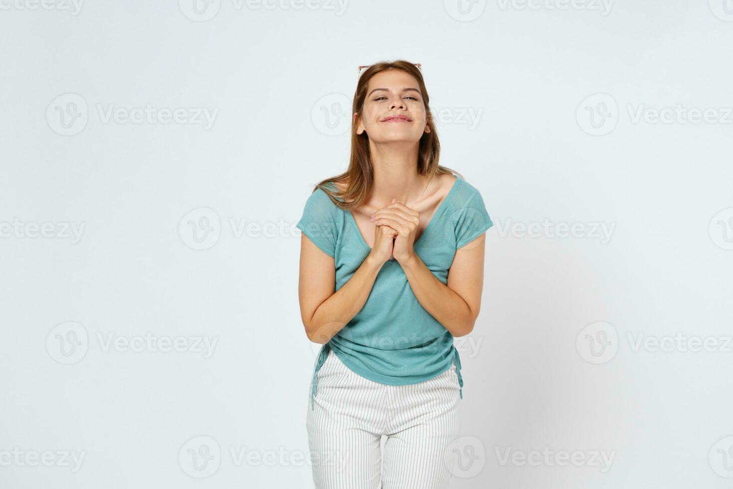 Happy young woman with a smile and clasped hands posing over a white background. photo