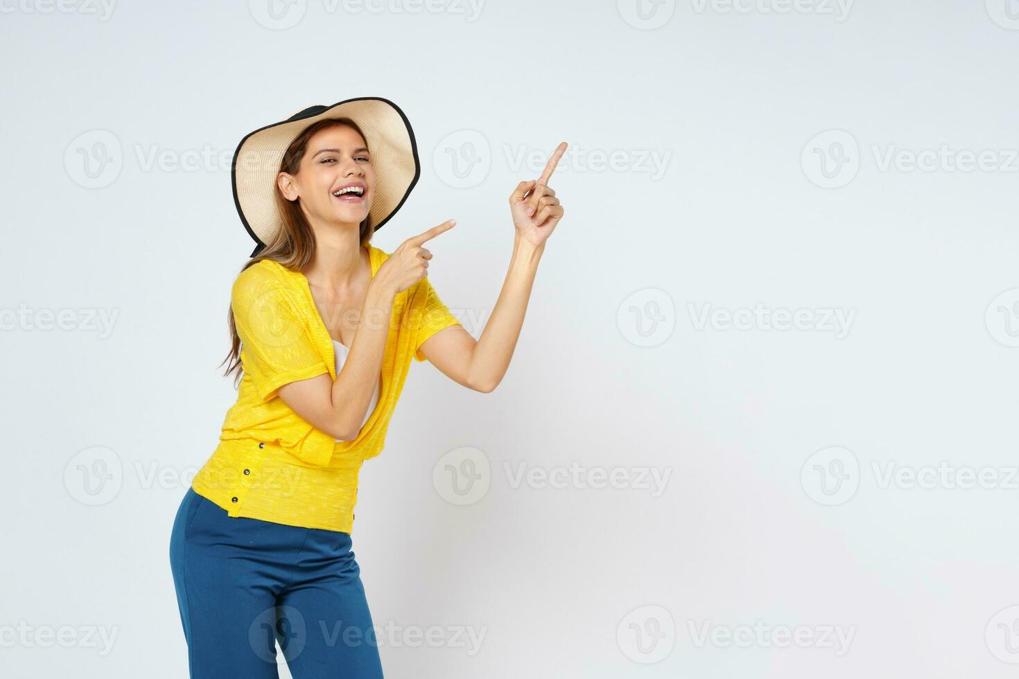 Young woman wearing sun hat and pointing to empty copy space isolated on white background. photo