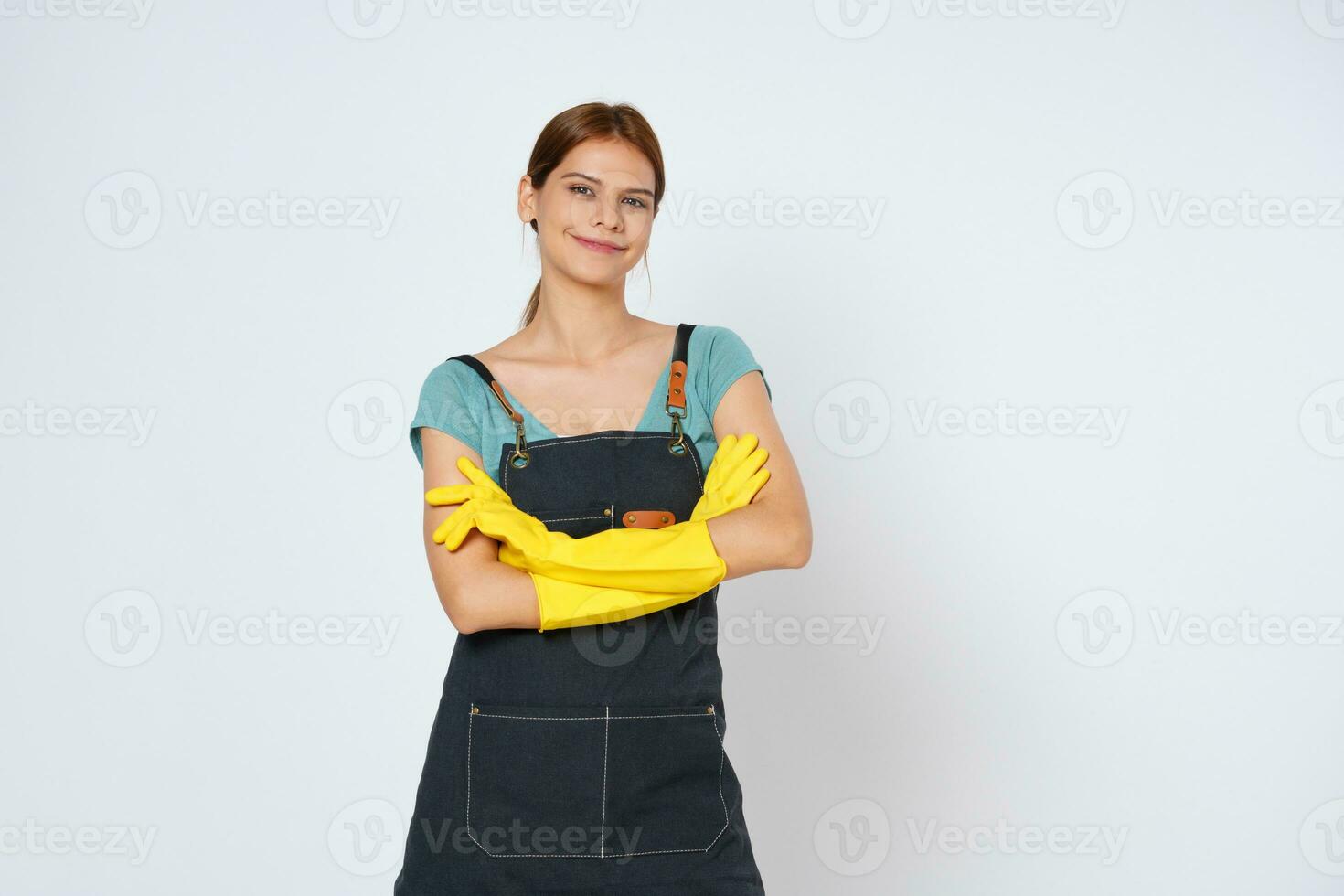 Young woman wearing yellow rubber gloves standing with arm crossed isolated over white background. photo