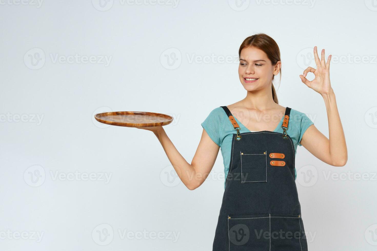 Restaurant owner sme woman showing OK sign and holding empty plate or dish isolated on white background. photo