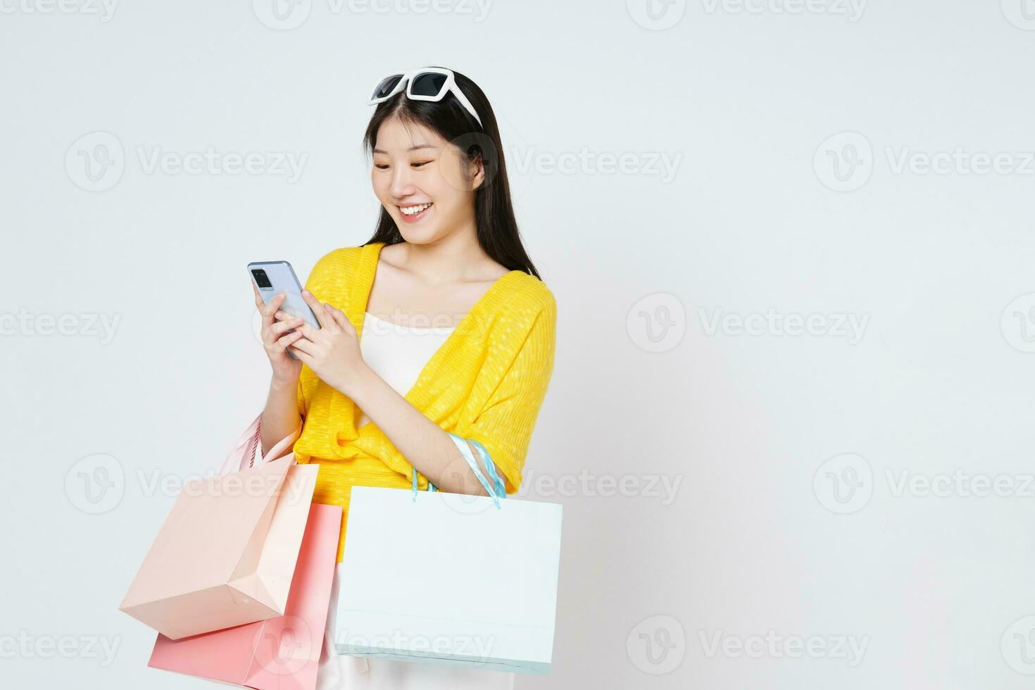 Young woman holding shopping bags while using mobile phone isolated over white background. photo