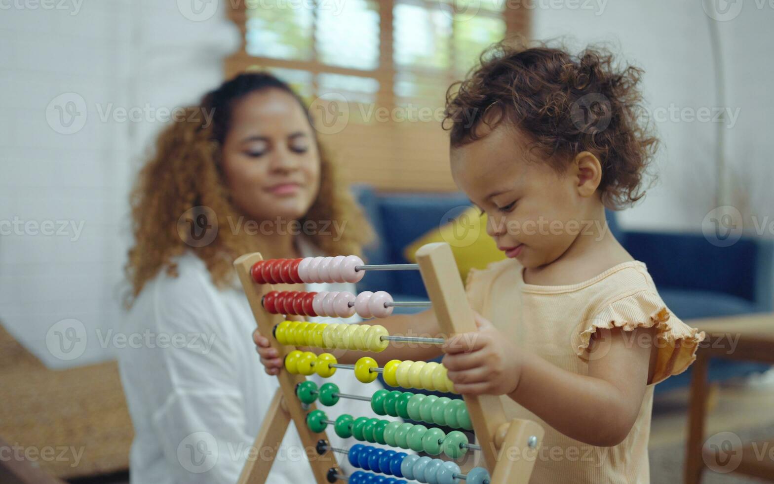 Mother and daughter are doing play a toy and having fun in living room. photo