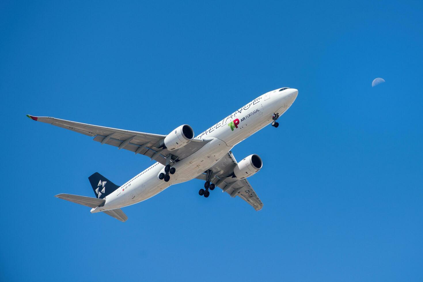 Portuguese company Tap with aircraft Airbus A330-941 approaching to land at Lisbon International Airport against blue sky photo