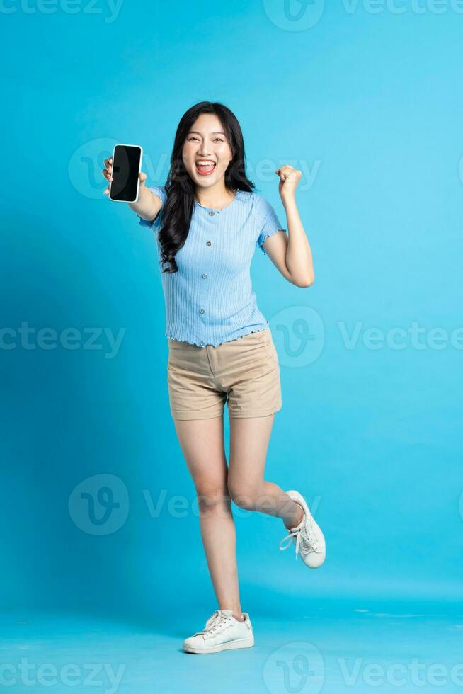 full body image of beautiful asian girl posing on blue background photo