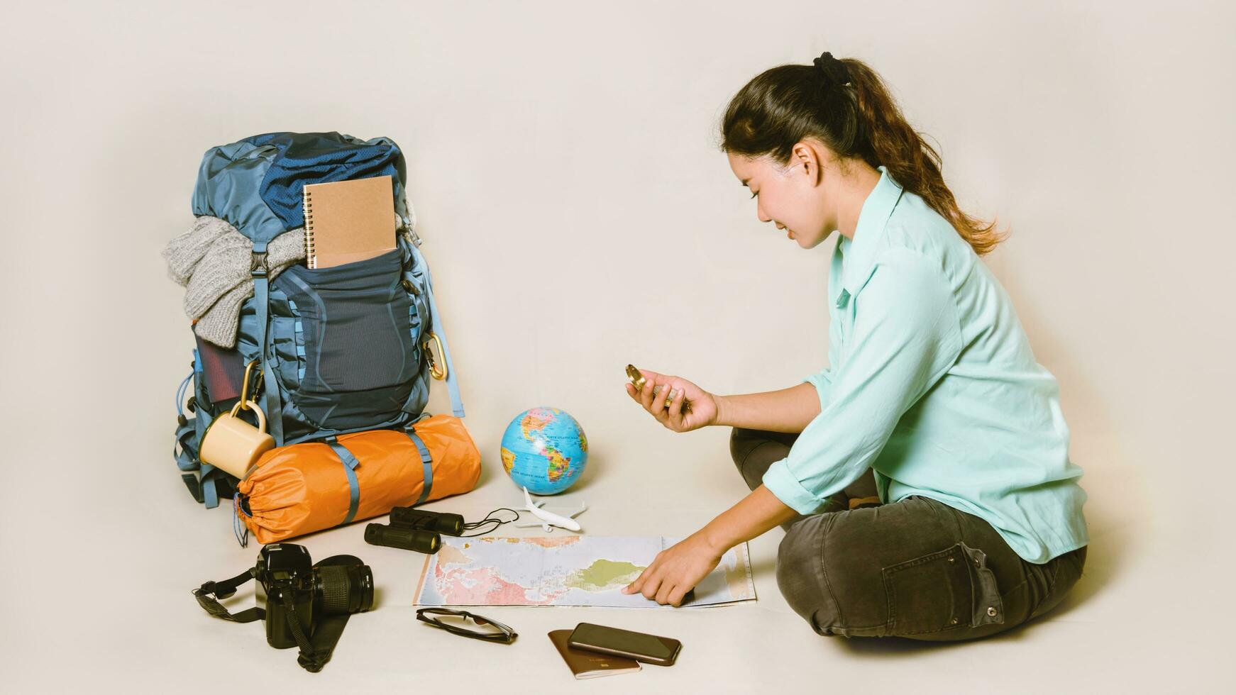 Tourist planning vacation with the help of world map with other travel accessories around. smartphone, film camera and sunglasses on a White background. Travel backpack photo