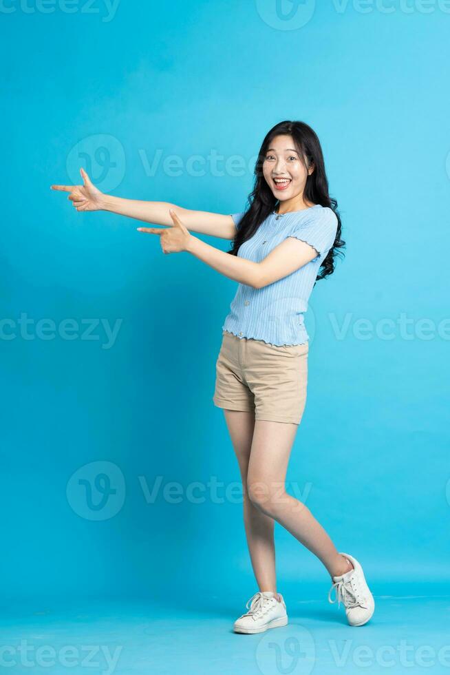 full body image of beautiful asian girl posing on blue background photo