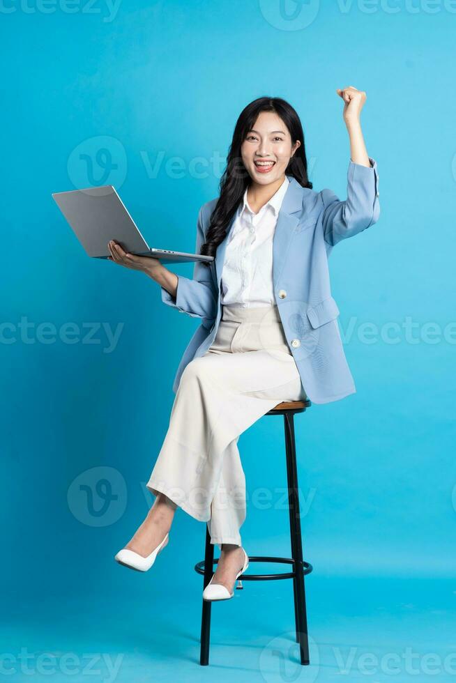Asian businesswoman portrait sitting on chair, isolated on blue background photo